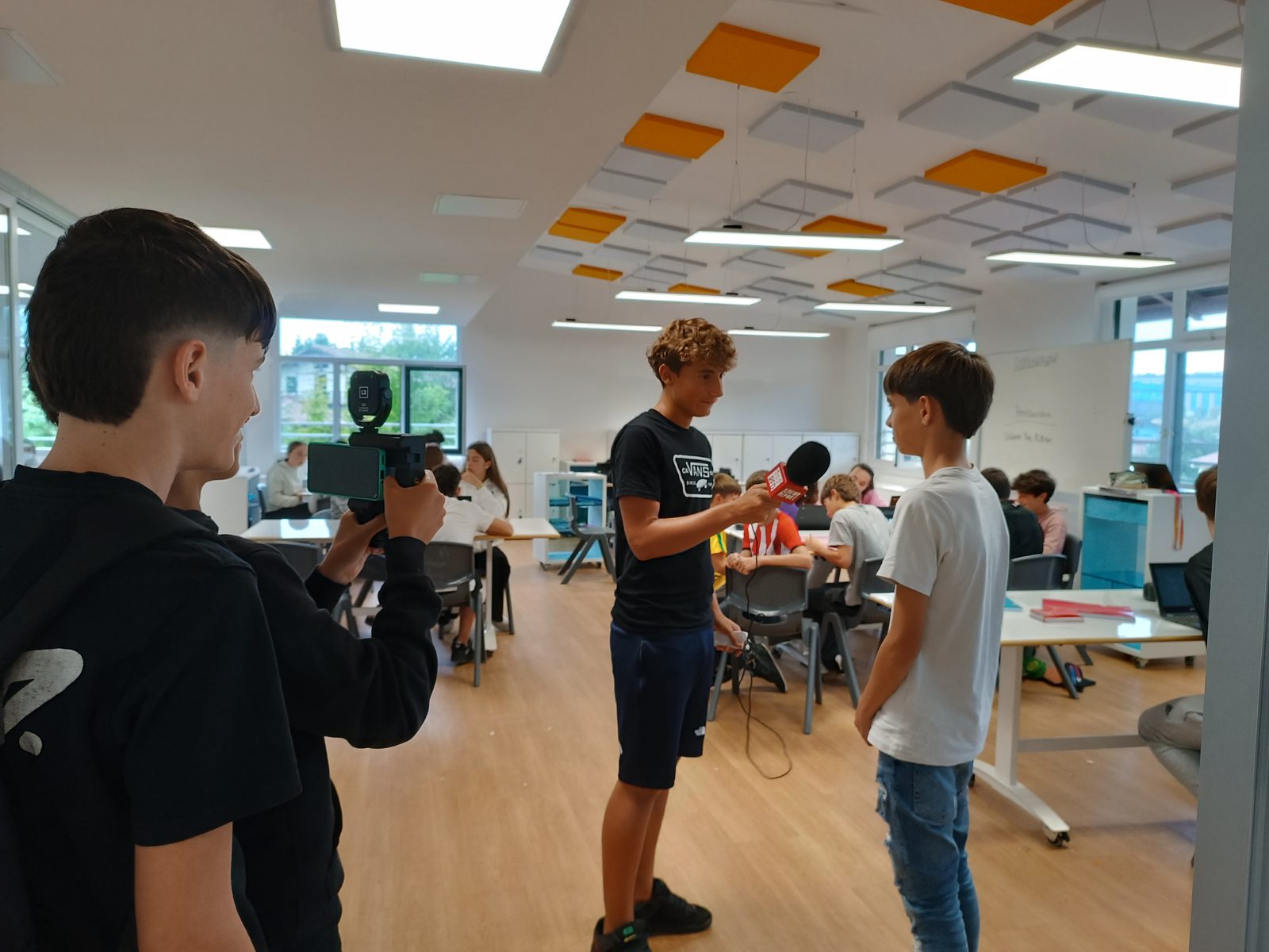 Alumnado trabajando como redactores: cámara, micrófono y entrevista en el aula