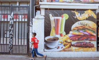 Un niño corre delante de un cartel de comida rápida hacia una tienda de caramelos en el centro de Santiago, Chile (UNICEF/UN0805425/Goupil)